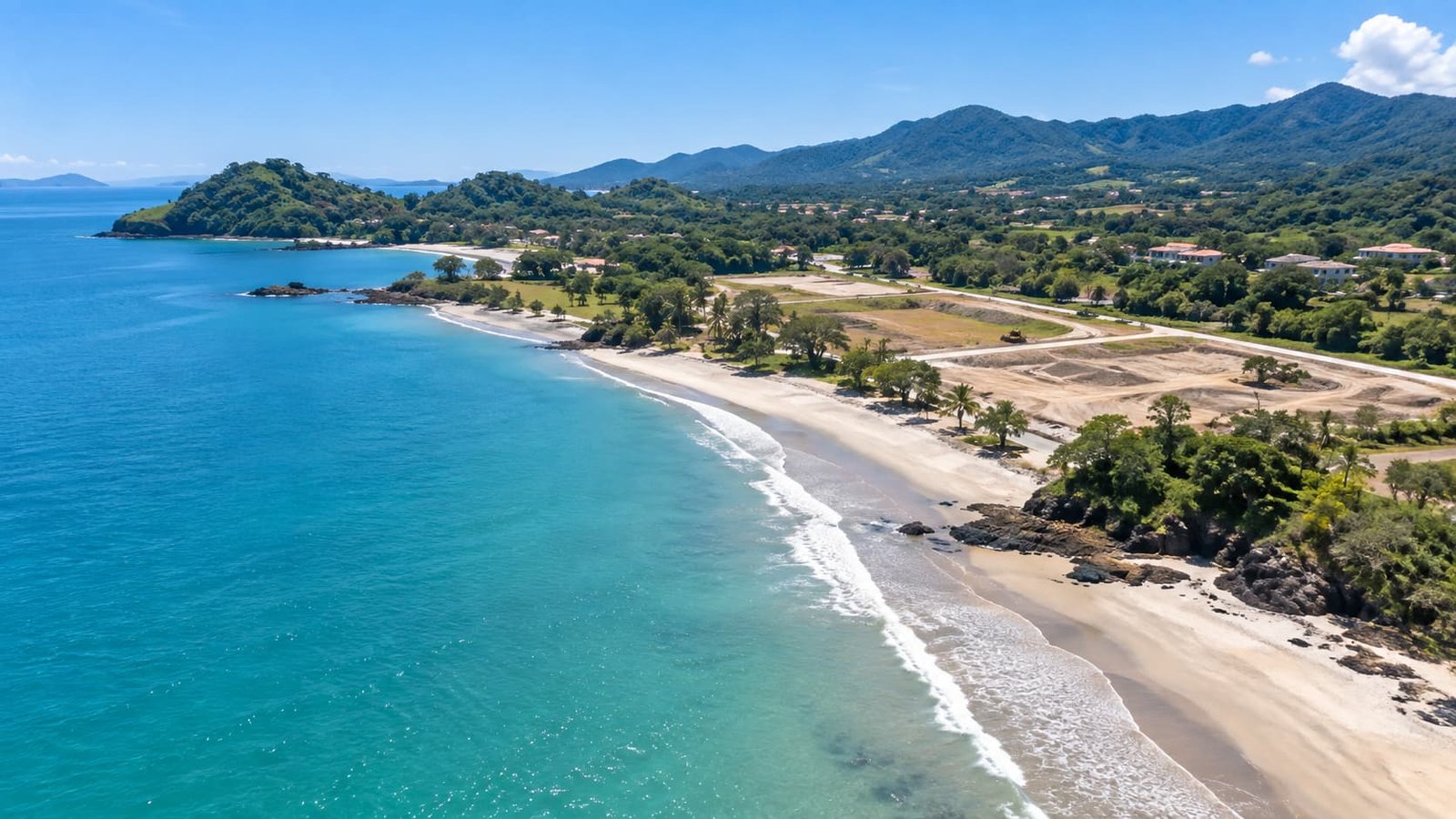 Vista aérea de una zona costera con playa, vegetación y terrenos cercanos al mar.